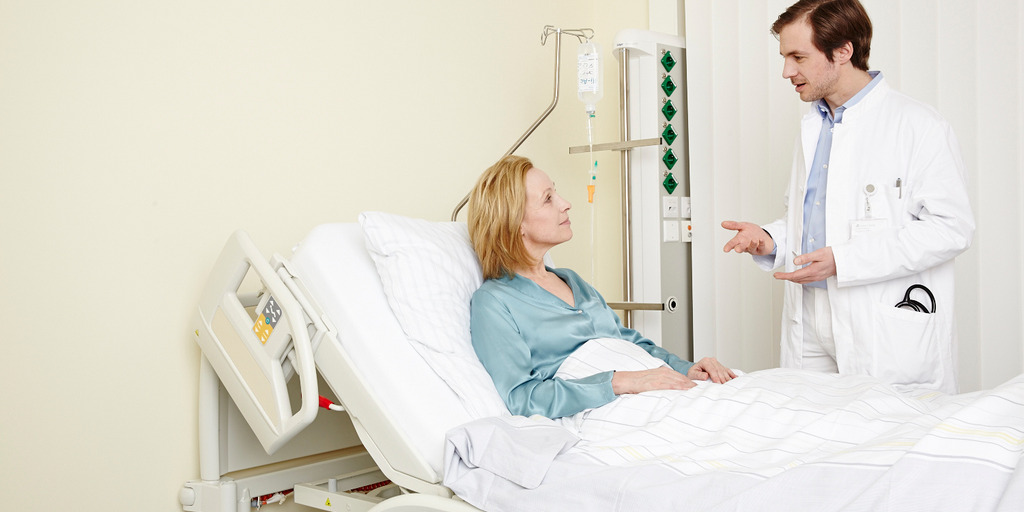 Arzt spricht mit Patientin am Krankenbett.