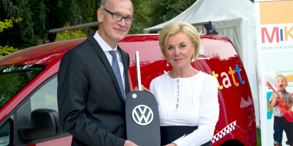 Dr. Eckhard Scholz und Liz Mohn mit einem überdimensional großen VW-Schlüssel vor einem VW Caddy.
