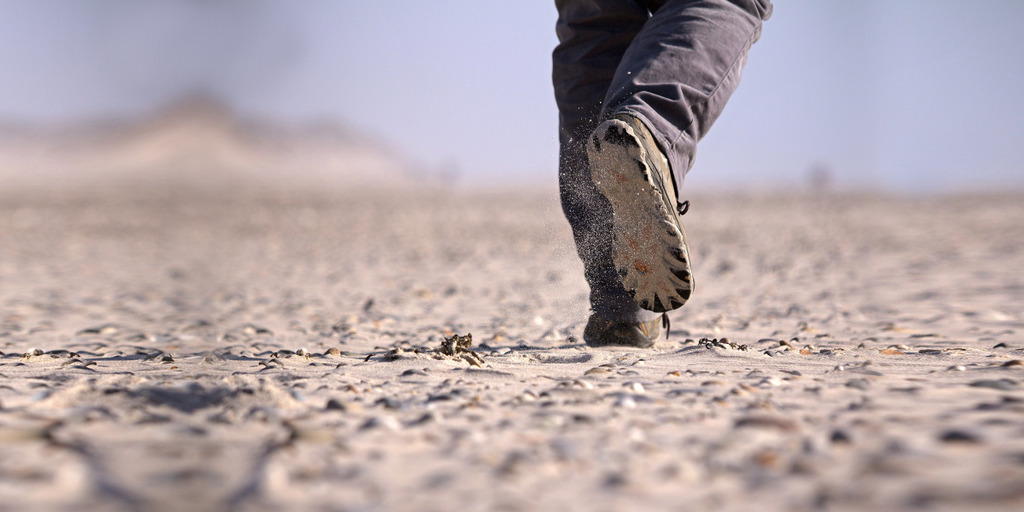 Zu sehen ist ein Mensch, der durch die Wüste läuft.