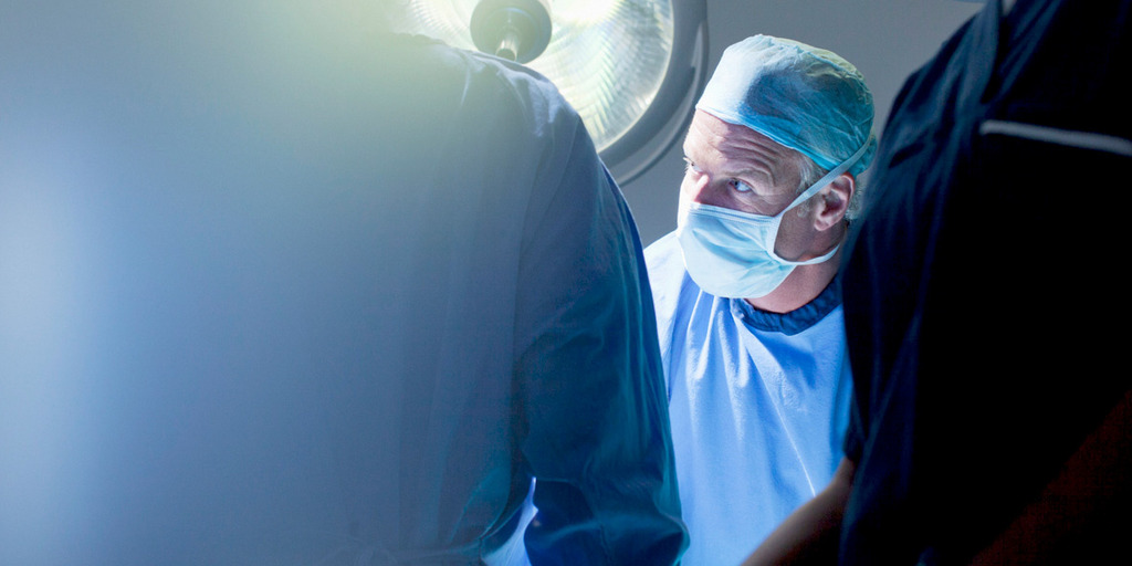Ein Arzt steht mit Kittel in einem OP-Raum