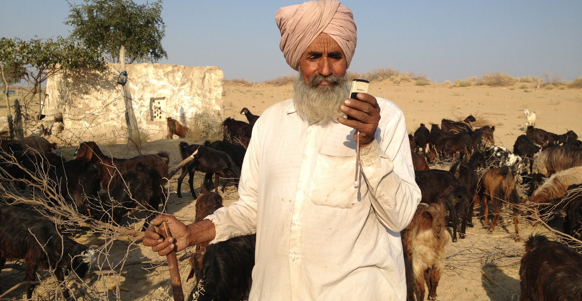 Ein Ziegenhirte im indischen Bundesstaat Rajasthan benutzt bei der Arbeit ein Smartphone.