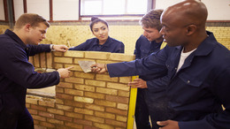 Lehrer hilft Auszubildenden im Bauberuf