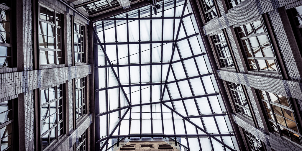 Der Blick zeigt von unten die Dachkonstruktion eines Gebäudes mit Glasdach.