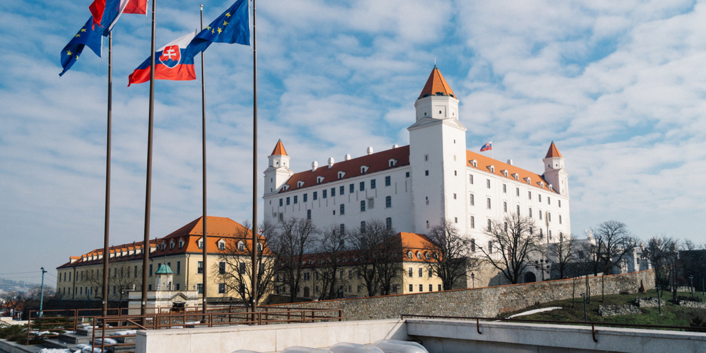 Blick auf die Burg der slowakische Hauptstadt Bratislava. Links daneben wehen slowakische und europäische Fahnen.