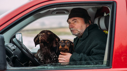 Heiner Sindel blickt aus dem geöffneten Fenster seines Autos. Er hat zwei Hunde auf seinem Schoß sitzen.
