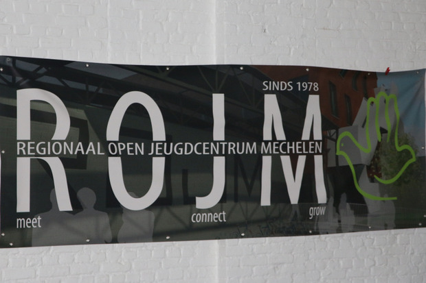 weiße Wand mit einem schwarzen Banner, auf dem "Regionaal open Jeugdcentrum Mechelen" steht