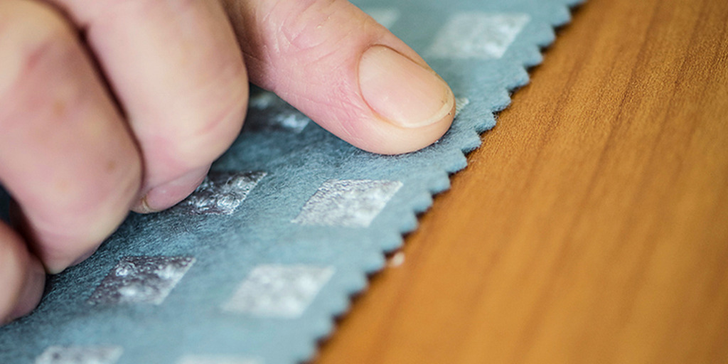 Ein Mann tastet ein Stück Stoff ab, auf dem mehrere Bereiche mit Braille-Schrift bestickt sind.