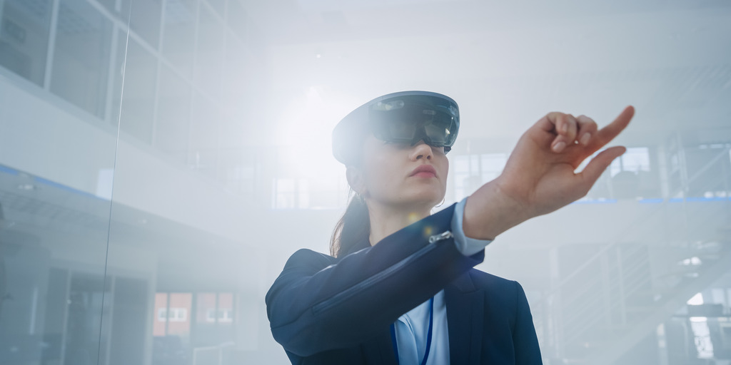Eine Frau nutzt eine Virtual Reality-Brille und drückt virtuelle Knöpfe in der Luft