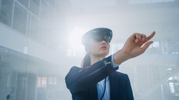 Eine Frau nutzt eine Virtual Reality-Brille und drückt virtuelle Knöpfe in der Luft
