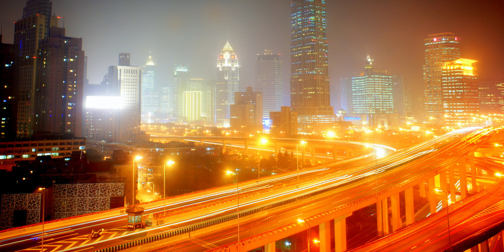 Es ist die Skyline von Shanghai bei Nacht zu sehen. Die Stadt steht im Smog.