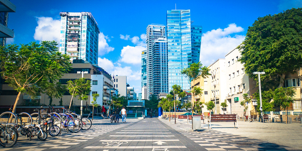 Blick auf eine Straße in Tel Aviv. Auf dem Boden sind breite Fahrradwege. Im Hintergrund viele Hochhäuser.
