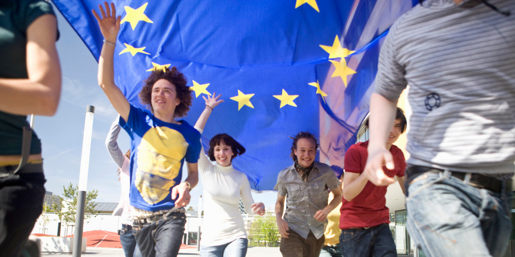Eine Gruppe junger Leute läuft fröhlich mit einer EU-Flagge durch München.