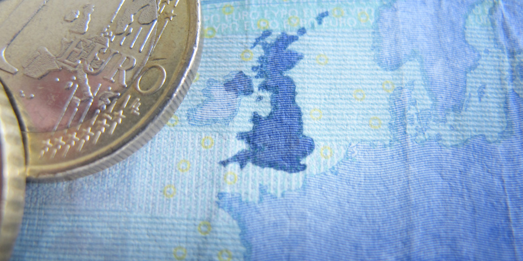 Großbritannien auf der auf einem 20-Euro-Schein aufgedruckten Europakarte, daneben eine 1-Euro-Münze.
