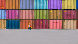 Viele bunte Container, die übereinander und nebeneinander gestapelt in einem Containerhafen stehen.
