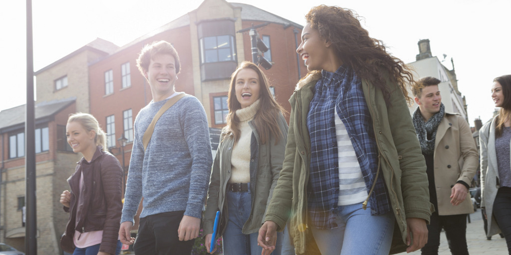 Eine Gruppe lächelnder junger Erwachsener auf dem Weg zur Uni
