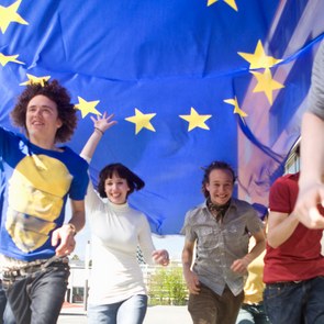 Einige Jungendliche laufen, die EU-Flagge in der Luft haltend, durch München.