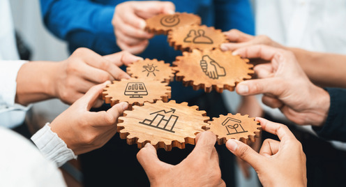 Hände halten Zahnräder in der Hand. Ein Konzept für Zusammenarbeit und Strategie, bei dem Holzzahnräder Ideen, Teamarbeit und Produktivität im geschäftlichen Umfeld symbolisieren