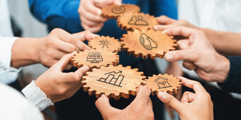 Hände halten Zahnräder in der Hand. Ein Konzept für Zusammenarbeit und Strategie, bei dem Holzzahnräder Ideen, Teamarbeit und Produktivität im geschäftlichen Umfeld symbolisieren