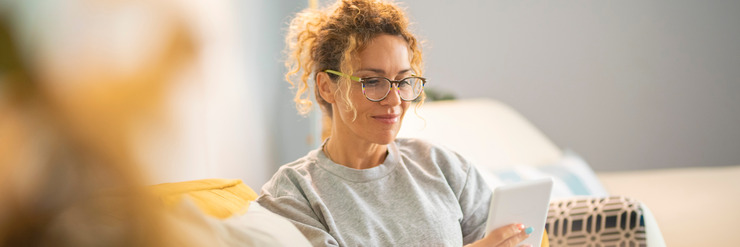 Frau liest auf dem Sofa in einem E-Reader