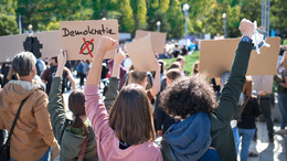 Gruppe von Menschen, die ein Pappschild mit der Aufschrift "Demokratie" hochhalten