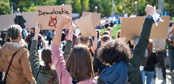 Rear view of people with placards and posters on global strike for climate change.(© Montage: © Halfpoint - stock.adobe.com)
