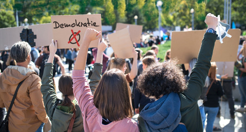 Gruppe von Menschen, die ein Pappschild mit der Aufschrift "Demokratie" hochhalten