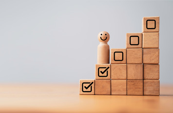 Holtz-Kl&ouml;tzchen stellen eine Treppen dar. Auf der steht eine Holzfigur. 2 Stufen haben ein OK_H&auml;kchen