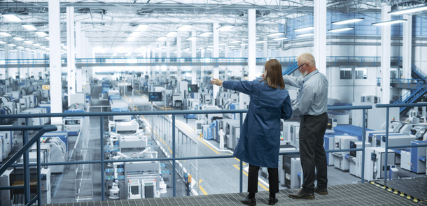 Experienced Male and Female Engineers Standing on a Platform with Their Back to Camera, Using Laptop Computer and Discussing Production at a Modern AI Automated Electronics Manufacture(© © Gorodenkoff - stock.adobe.com)