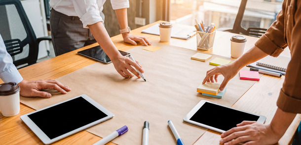 Creative business team brainstorming ideas, writing on large paper with markers and using digital tablets.(© © Jonathan - stock.adobe.com)