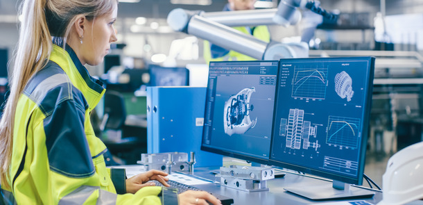 At the Factory: Female Mechanical Engineer Designs 3D Engine on Her Personal Computer, Male Automation Engineer Uses Laptop for Programming Robotic Arm.(© Gorodenkoff Productions OU)