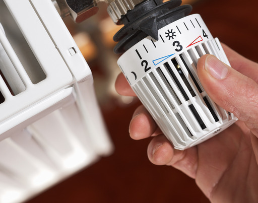 Hand dreht am Heizungsthermostat