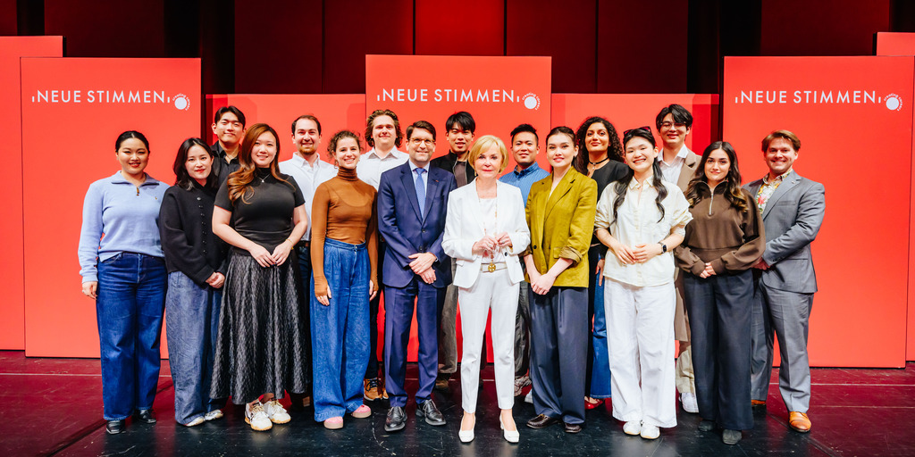 Gruppenfoto der Semifinalist:innen der NEUEN STIMMEN 2026 mit NEUE-STIMMEN-Präsidentin Liz Mohn und Alexander Neef, Vorsitzender der Jury der NEUEN STIMMEN.