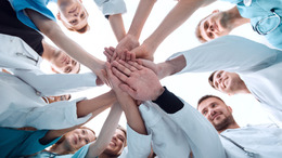 Medizinische Personal steht im Kreis und alle stapeln ihre Hände in der Mitte übereinander