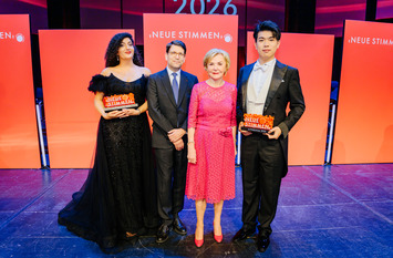 Die Gewinner:innen der NEUEN STIMMEN 2026, Arpi Sinanyan und Jiazhou Wang, posieren nach dem Finalkonzert mit Liz Mohn, Pr&auml;sidentin der NEUEN STIMMEN und Vorsitzende des Vorstands der Liz Mohn Stiftung, und dem Juryvorsitzenden der NEUEN STIMMEN, Alexander Neef, f&uuml;r ein Foto.