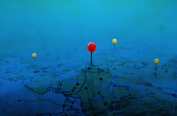 Pins on a geographic map curved like mountains. Pinning a location on a map with mountains.