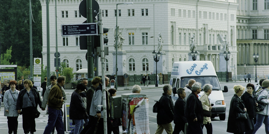 Foto der Bertelsmann Repräsentanz Unter den Linden 1 in Berlin von etwas weiter entfernt mit Fußgängern auf der Straße davor