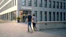 Außenaufnahme eines Jobcenters, in das mehrere Personen gehen.