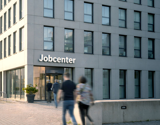 Außenaufnahme eines Jobcenters, in das mehrere Personen gehen.