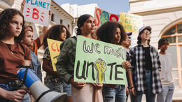Junge Frauen und Männer halten Schilder bei einer Demonstration hoch.