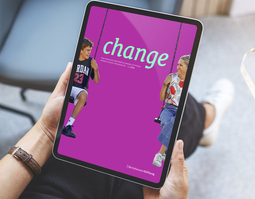 Eine Frau sitzt mit einem Tablet in ihren Händen, auf dem das Titelbild der aktuellen change-Ausgabe zu sehen ist.