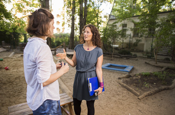 Zwei Frauen unterhalten sich auf einem Spielplatz