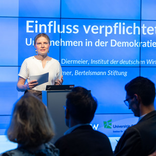 Mann spricht vor Medienwand