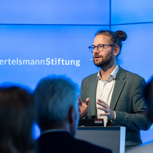 Mann spricht vor Medienwand
