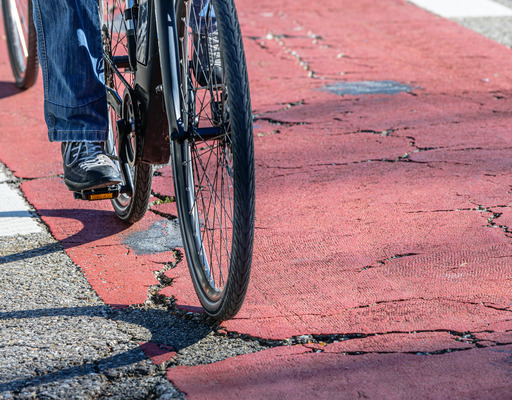 Fahrrad fährt auf beschädigtem Radweg