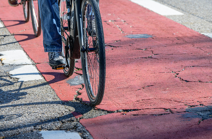 Fahrrad f&auml;hrt auf einem besch&auml;digten Radweg