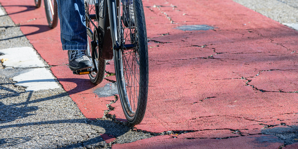 Fahrrad fährt auf einem beschädigten Radweg