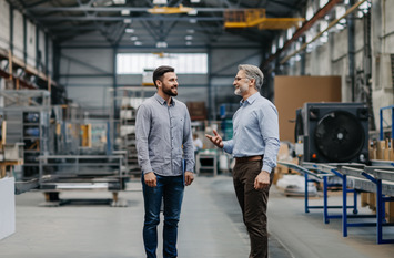 Zwei M&auml;nner unterhalten sich in einer Lagerhalle