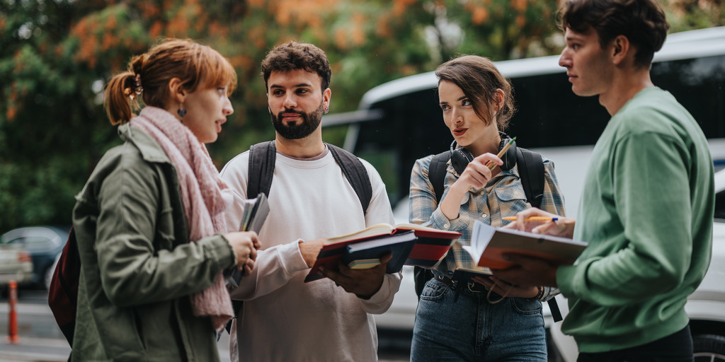 Group of students discussing with books outside 