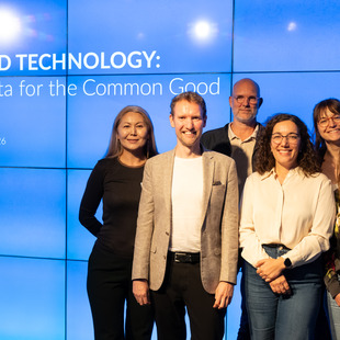 Sechs Personen stehen vor einer blauen Wand mit der Aufschrift 'BEYOND TECHNOLOGY: AI & Data for the Common Good 17. September 2026' und lächeln in die Kamera