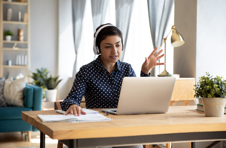Frau mit Kopfh&ouml;rern sitzt im Homeoffice am Schreibtisch